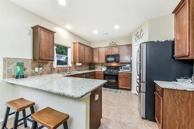 a kitchen with stainless steel appliances granite countertop a table chairs sink refrigerator and microwave