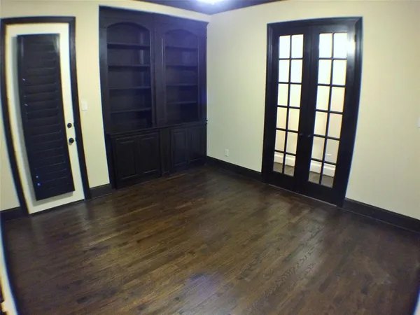 a view of an empty room with wooden floor and closet