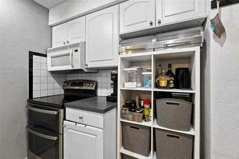 a kitchen with white cabinets and appliances