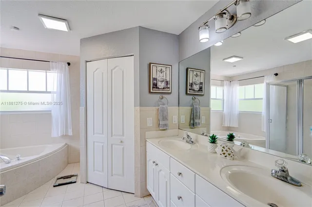 a bathroom with double vanity sinks a large mirror and a bathtub