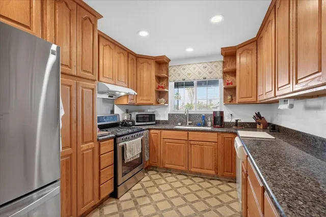 a kitchen with granite countertop a sink stainless steel appliances and cabinets