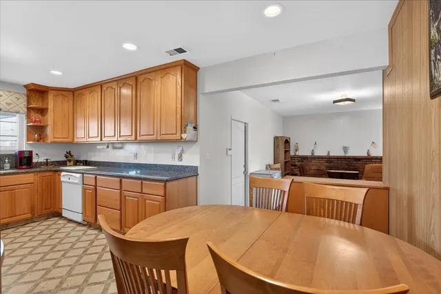 a kitchen with stainless steel appliances granite countertop a sink a stove a refrigerator cabinets and dining table