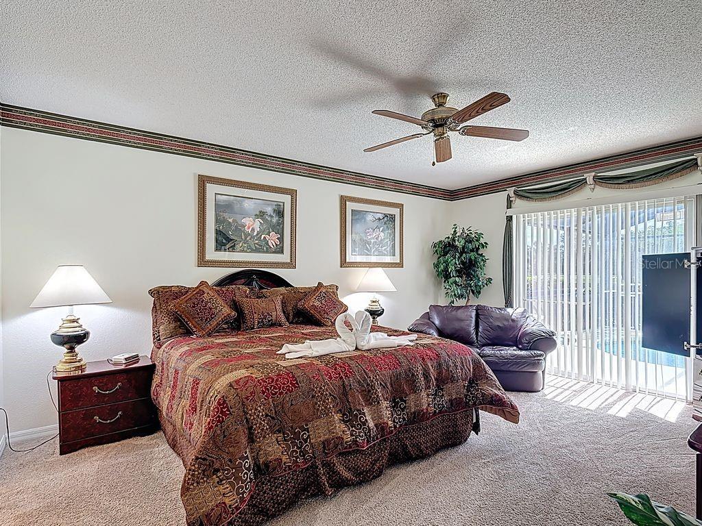 955 Lake Berkley Drive Kissimmee, FL 34746 - Photo 18 of 57 a spacious bedroom with two beds and a chandelier