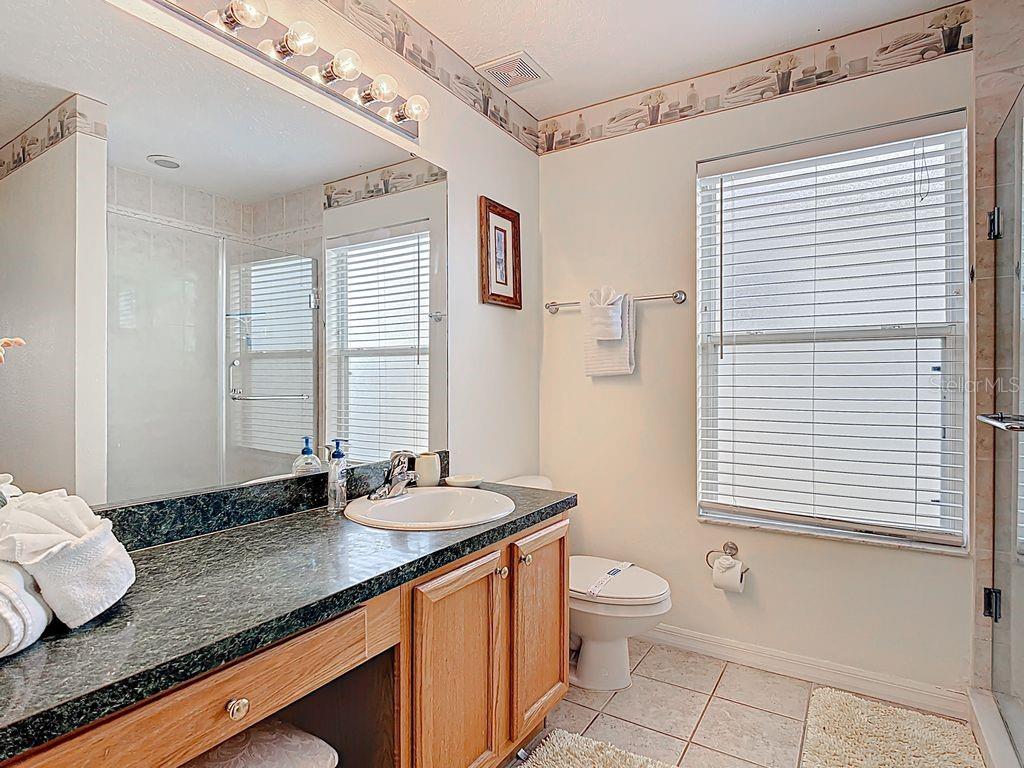 955 Lake Berkley Drive Kissimmee, FL 34746 - Photo 26 of 57 a bathroom with a granite countertop sink toilet a mirror and shower