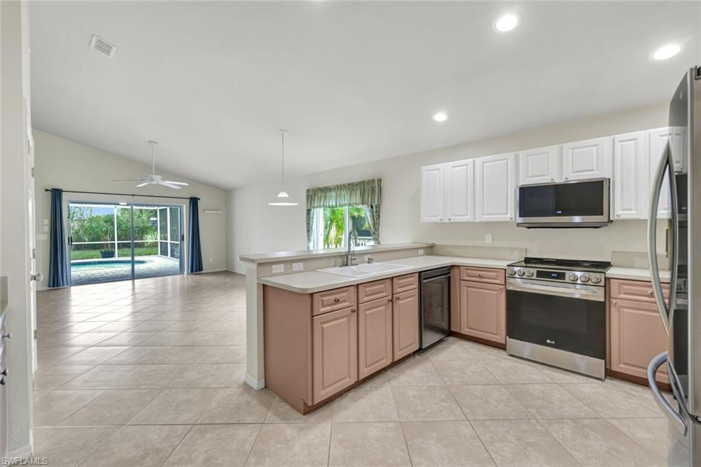 15645 Beachcomber Avenue Fort Myers, FL 33908 - Photo 13 of 33 a kitchen with stainless steel appliances granite countertop a stove top oven a sink dishwasher a dining table and chairs with wooden floor