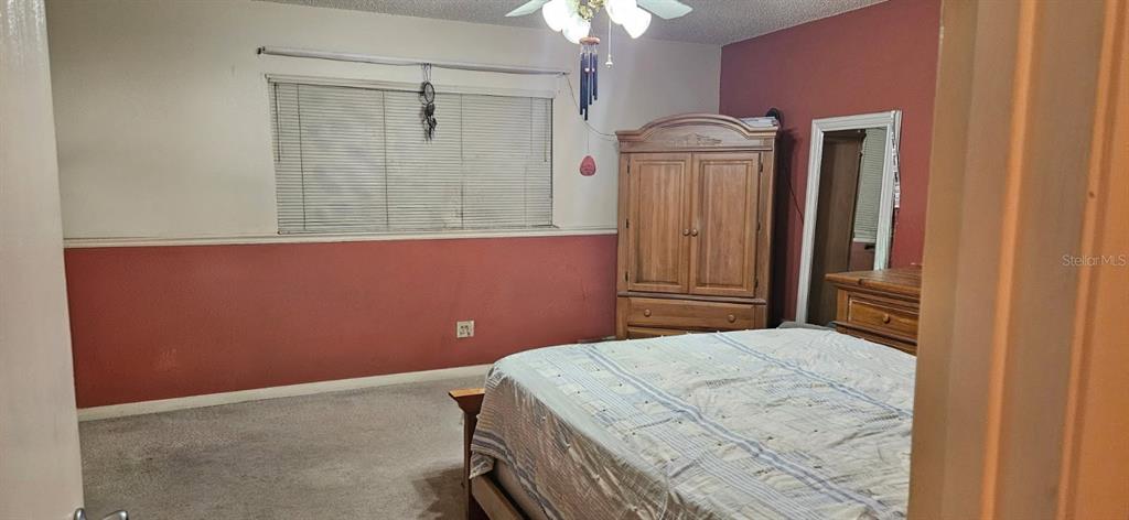 8666 Southwest 92nd Lane, Unit F Ocala, FL 34481 - Photo 8 of 12 a bedroom with a bed and a chandelier