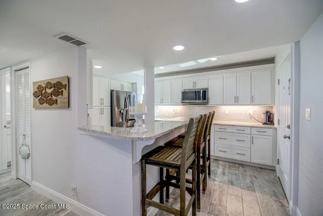a kitchen with kitchen island a dining table chairs refrigerator and cabinets