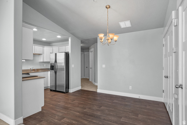 2457 West 500 South, Unit 2 Springville, UT 84663 - Photo 12 of 27 Open-concept living space featuring wood-finish flooring, a contemporary chandelier, and a kitchen with white cabinetry and stainless steel appliances
