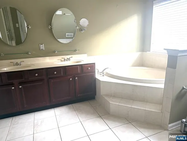 a bathroom with a double vanity sink mirror and bathtub
