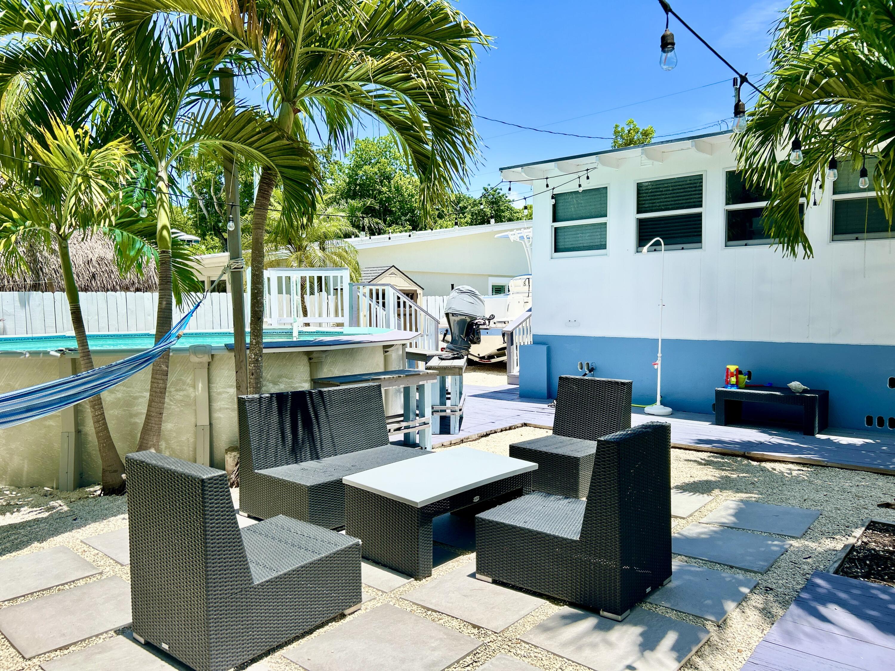 124 South Bay Harbor Drive Key Largo, FL 33037 - Photo 16 of 43 a view of a patio with couches table and chairs with wooden floor and fence