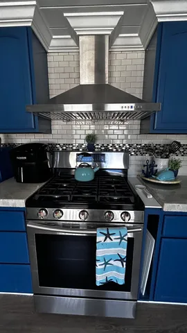 a kitchen with stainless steel appliances granite countertop a sink a stove and cabinets