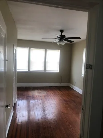 a view of an empty room with a window and wooden floor