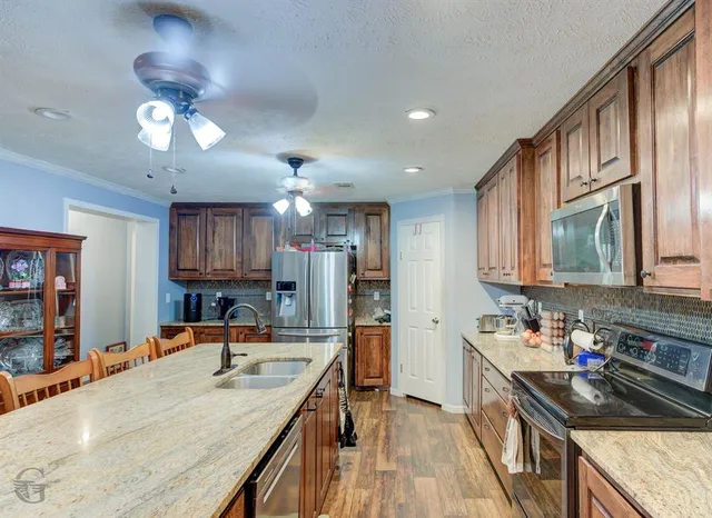a kitchen with kitchen island granite countertop a sink appliances cabinets and a counter top space