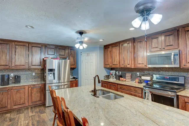 a kitchen with stainless steel appliances granite countertop a refrigerator and a stove top oven