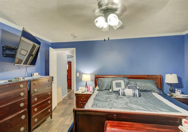 a bedroom with a bed and a flat tv screen on dresser