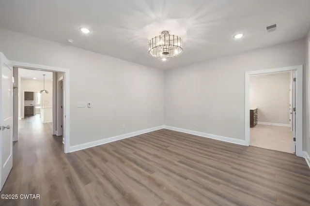 a view of an empty room with wooden floor and window