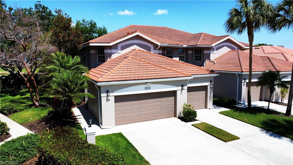 2033 Crestview Way, Unit 104 Naples, FL 34119 - Photo 1 of 24 a front view of a house with a yard and garage
