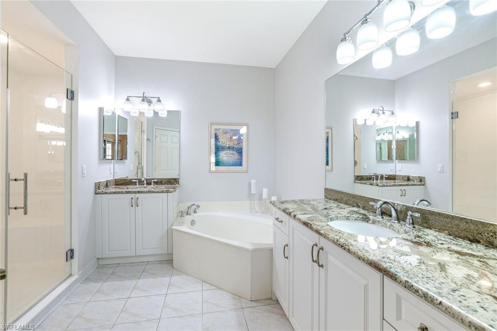 2033 Crestview Way, Unit 104 Naples, FL 34119 - Photo 11 of 24 a bathroom with a granite countertop sink a large mirror and a bathtub