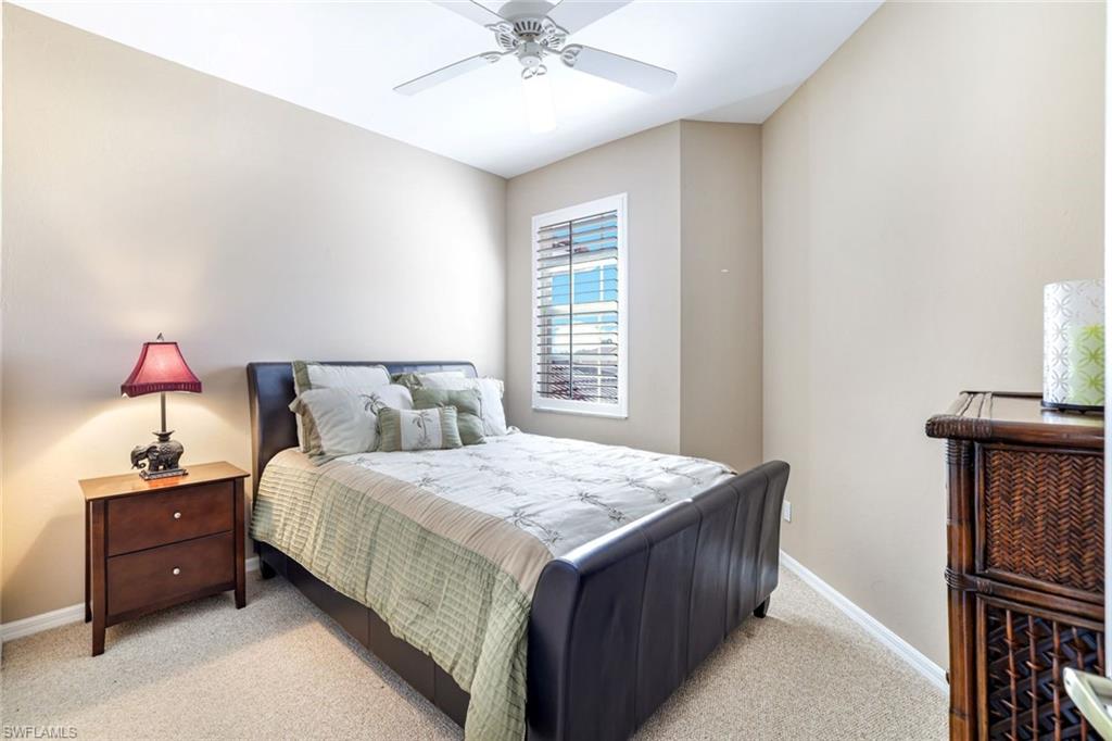 2033 Crestview Way, Unit 104 Naples, FL 34119 - Photo 12 of 24 a bedroom with a bed and a chandelier