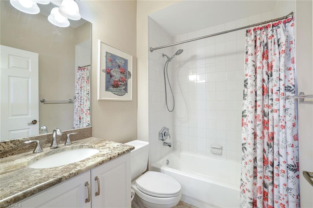 2033 Crestview Way, Unit 104 Naples, FL 34119 - Photo 13 of 24 a bathroom with a granite countertop sink a toilet and a bathtub