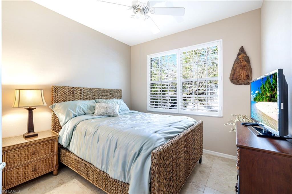 2033 Crestview Way, Unit 104 Naples, FL 34119 - Photo 14 of 24 a spacious bedroom with a bed and a flat tv screen on dresser