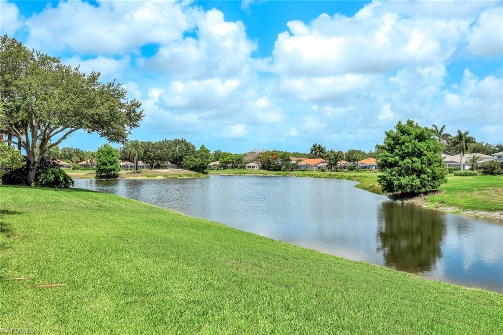 2033 Crestview Way, Unit 104 Naples, FL 34119 - Photo 18 of 24 a view of a lake with houses in the background