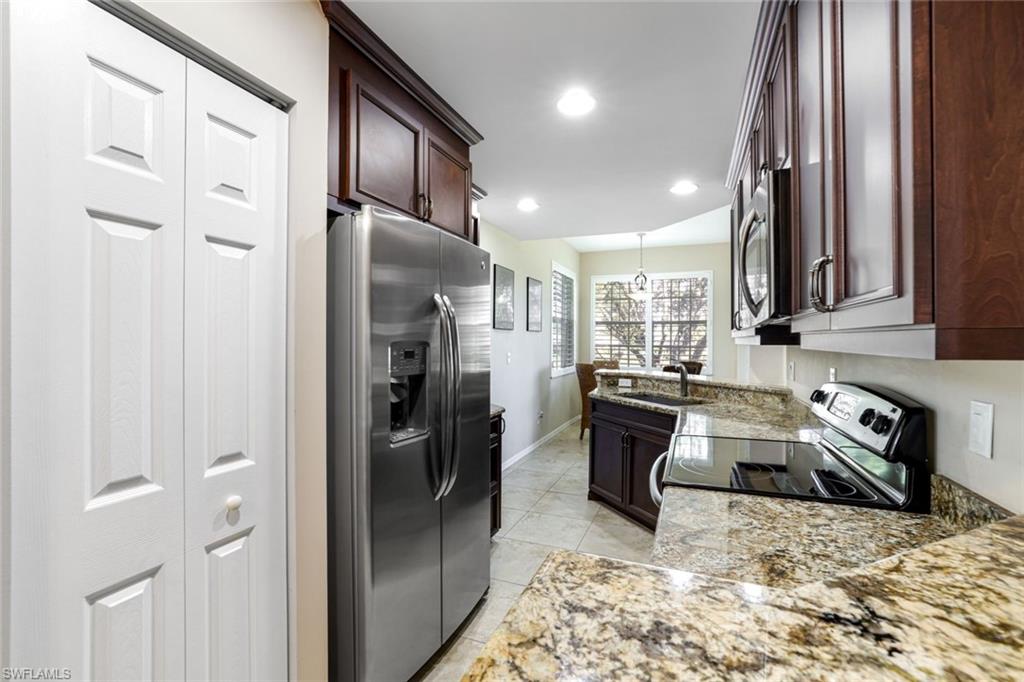 2033 Crestview Way, Unit 104 Naples, FL 34119 - Photo 4 of 24 a kitchen with refrigerator and cabinets