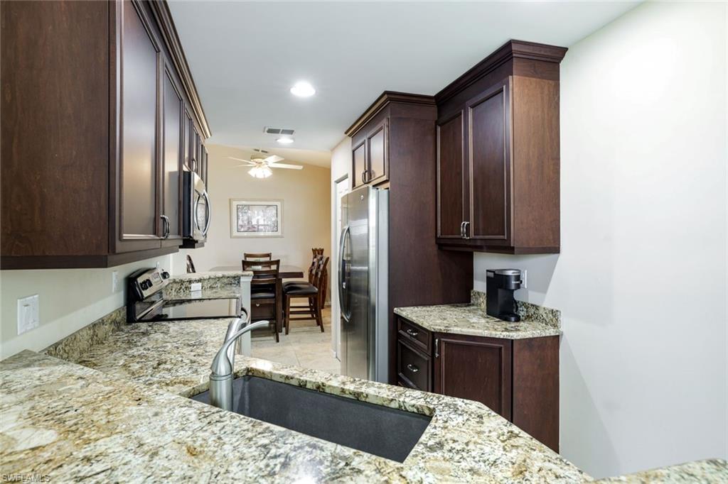 2033 Crestview Way, Unit 104 Naples, FL 34119 - Photo 5 of 24 a kitchen with stainless steel appliances granite countertop a sink stove and refrigerator