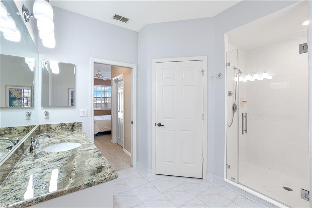 2033 Crestview Way, Unit 104 Naples, FL 34119 - Photo 10 of 24 a spacious bathroom with a granite countertop mirror and shower