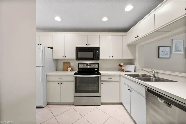 a kitchen with a sink white cabinets and stainless steel appliances
