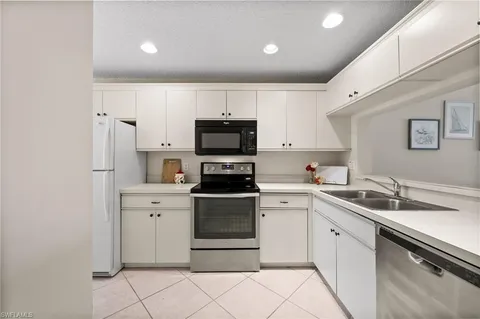 a kitchen with a sink white cabinets and stainless steel appliances