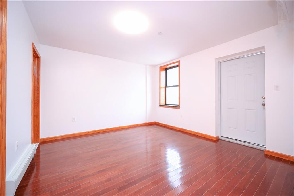 1270 64th Street, Unit 1B Brooklyn, NY 11219 - Photo 11 of 13 an empty room with wooden floor and windows
