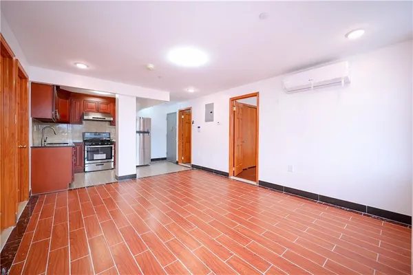 a view of kitchen with stainless steel appliances wooden floor and an empty room