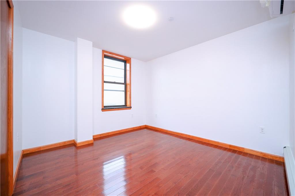 1270 64th Street, Unit 1B Brooklyn, NY 11219 - Photo 10 of 13 an empty room with wooden floor and windows