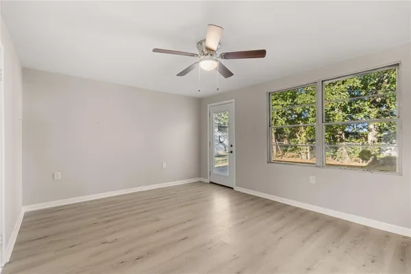a view of an empty room with wooden floor and a window