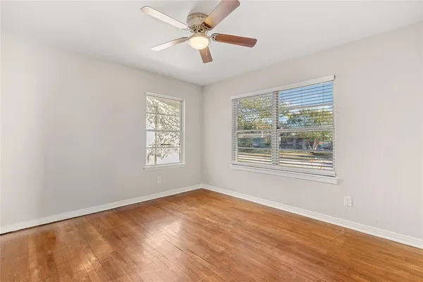 a view of an empty room with wooden floor and a window