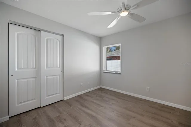 an empty room with wooden floor and ceiling fan