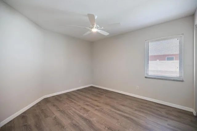 wooden floor in an empty room with a chandelier fan