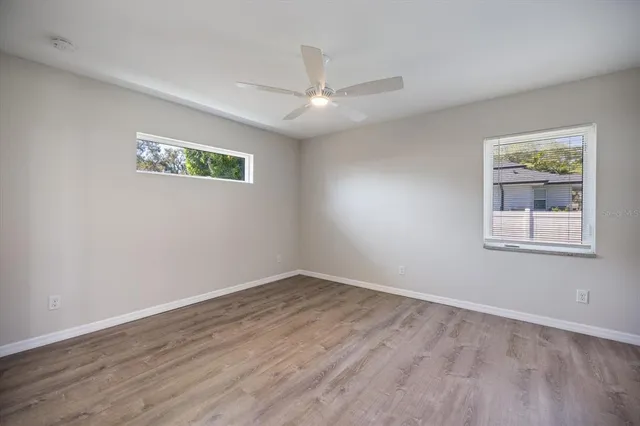 an empty room with wooden floor and a ceiling fan