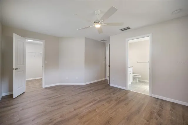 a view of an empty room with wooden floor and a ceiling fan