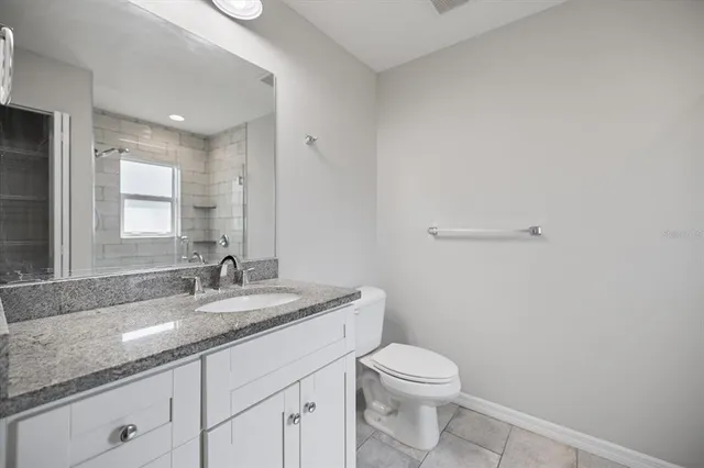 a bathroom with a granite countertop sink a toilet and a mirror