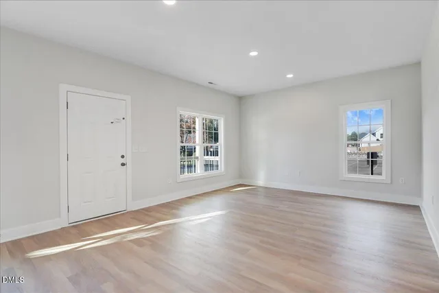 a view of an empty room with a window and wooden floor