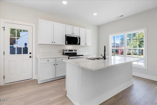 a kitchen with stainless steel appliances a stove a sink a microwave and cabinets