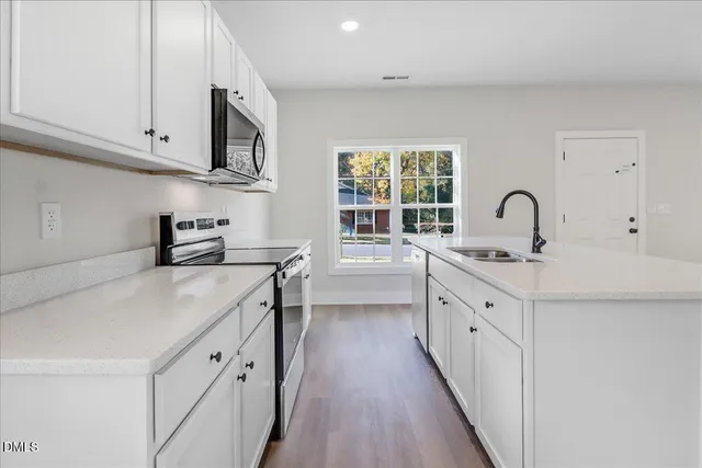 a kitchen with granite countertop a sink stove and cabinets