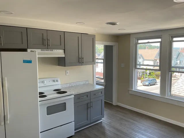 a kitchen with granite countertop white cabinets and white appliances