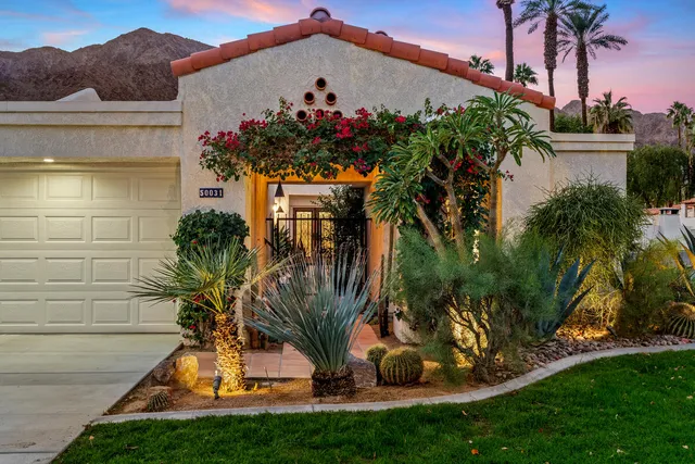a view of a white house with a yard and potted plants