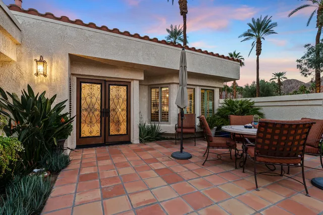 a view of a patio with a table and chairs potted plants and palm tree