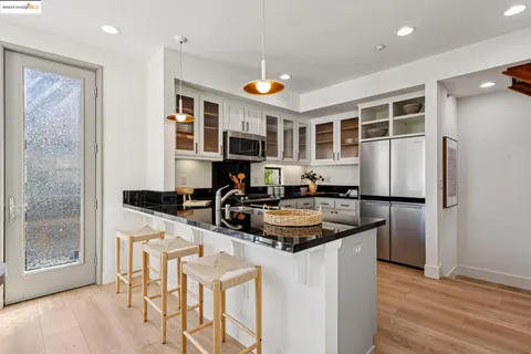 a kitchen with stainless steel appliances granite countertop a refrigerator a stove and a sink with wooden floor