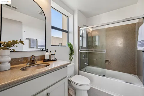 a bathroom with a granite countertop sink toilet and shower