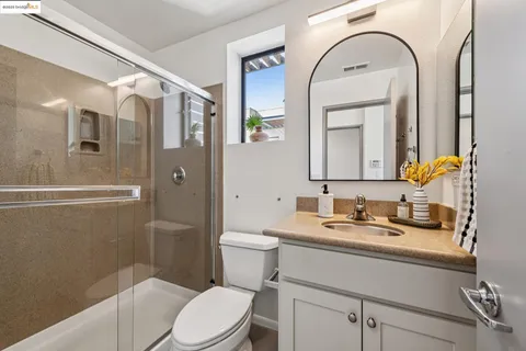 a bathroom with a toilet a sink a mirror a vanity and shower